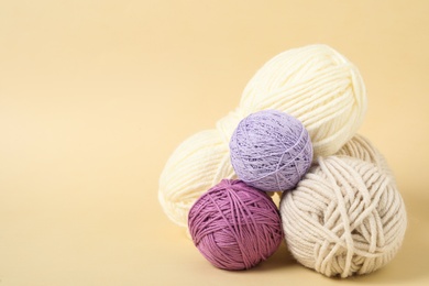 Photo of Soft colorful woolen yarns on beige background. Space for text