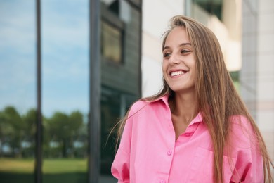 Beautiful young woman in stylish shirt near building outdoors, space for text