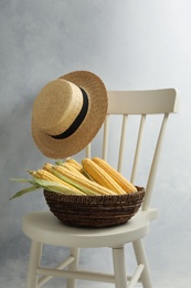 Photo of Bowl of corn cobs on chair near grey wall