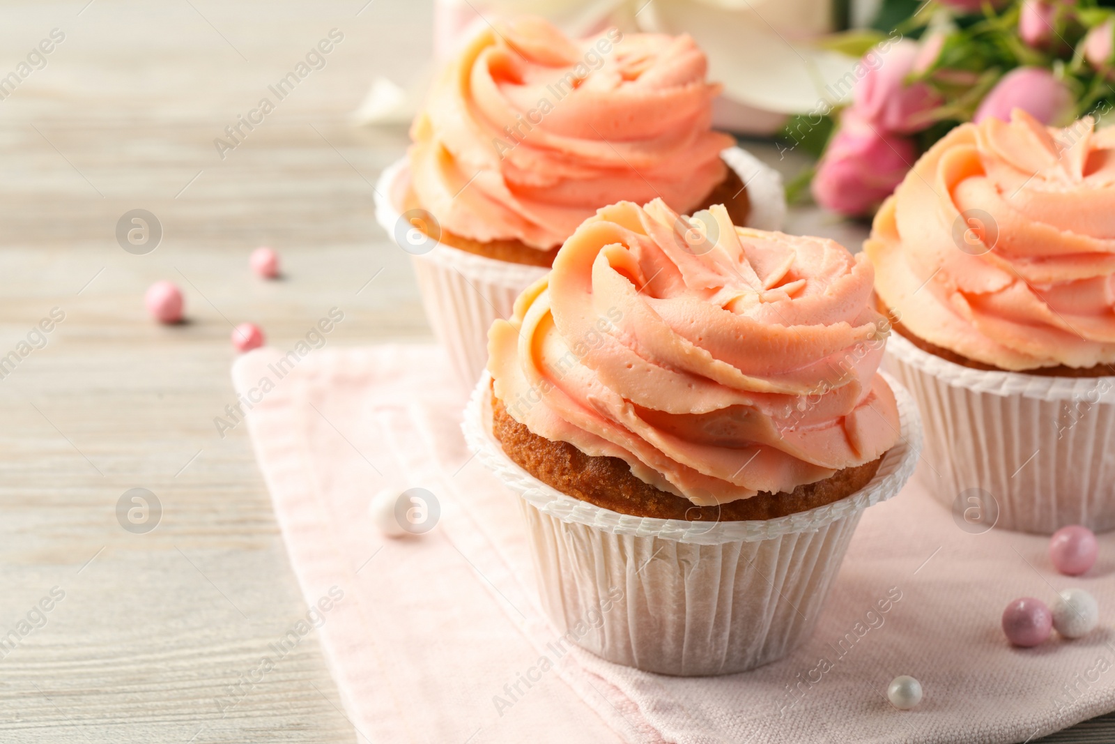 Photo of Tasty cupcakes with cream on wooden table, closeup