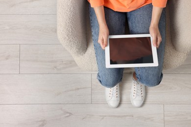 Photo of Woman working with tablet in armchair, top view. Space for text