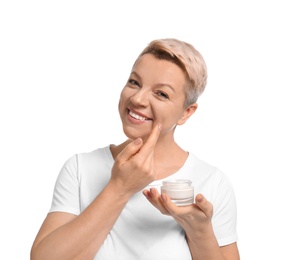 Mature woman applying face cream on white background