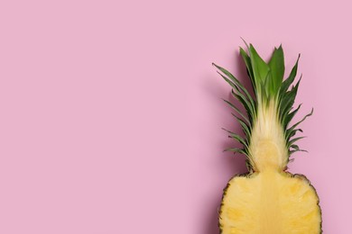 Photo of Half of ripe pineapple on pale pink background, top view. Space for text