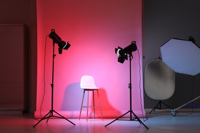 Photo of Photo background in neon lights and professional lighting equipment inside modern studio