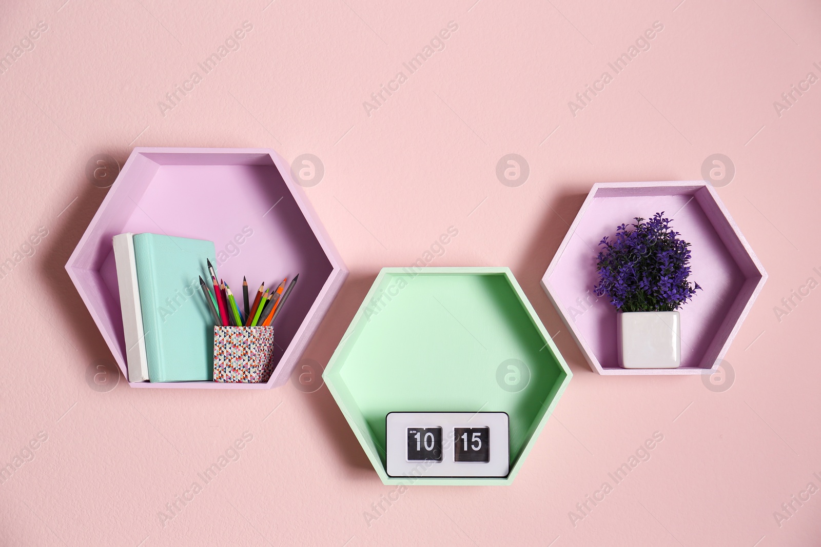 Photo of Hexagon shaped shelves on pink wall. Interior design