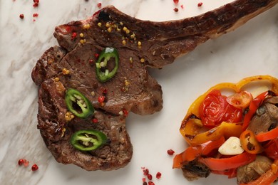 Delicious fried beef meat served with vegetables on marble board, top view