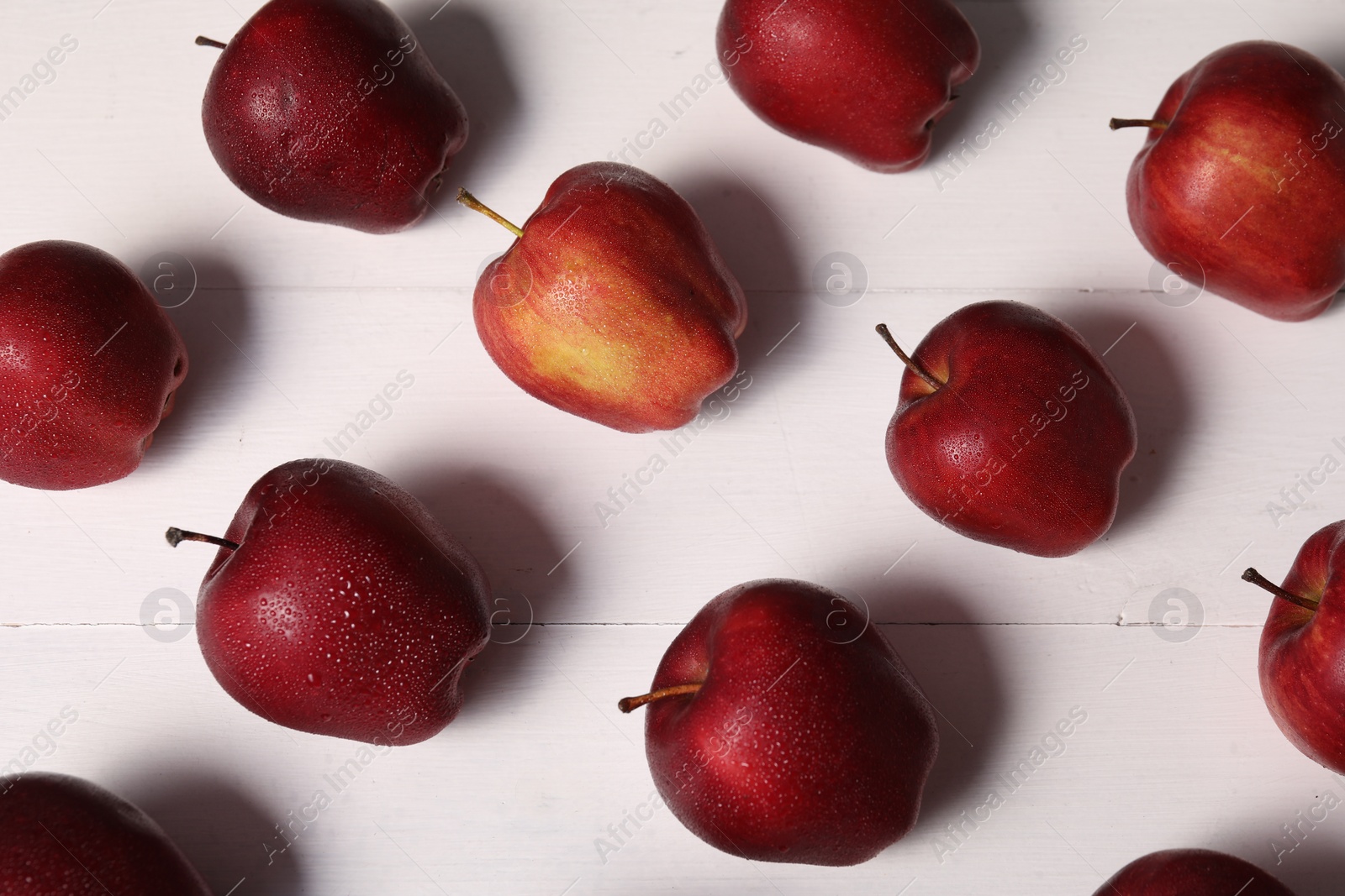 Photo of Fresh red apples with water drops on white wooden table, flat lay