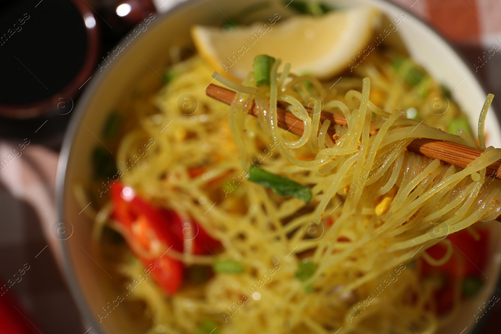 Photo of Stir-fry. Eating tasty noodles with chopsticks at table, closeup and space for text