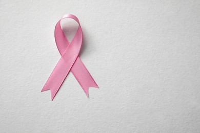 Pink ribbon on white background, top view with space for text. Breast cancer awareness concept