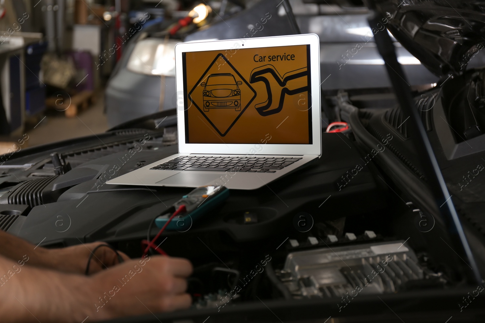 Photo of Mechanic with laptop doing car diagnostic at automobile repair shop, closeup