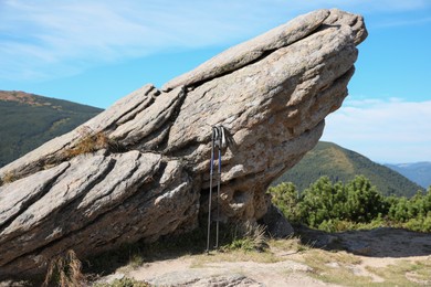 Photo of Trekking poles near rock in mountains. Hiking accessory