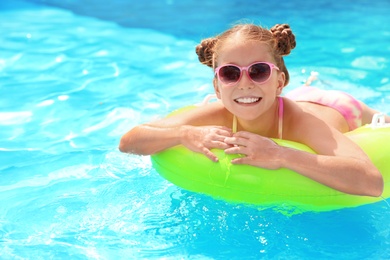 Photo of Little girl with inflatable ring in swimming pool