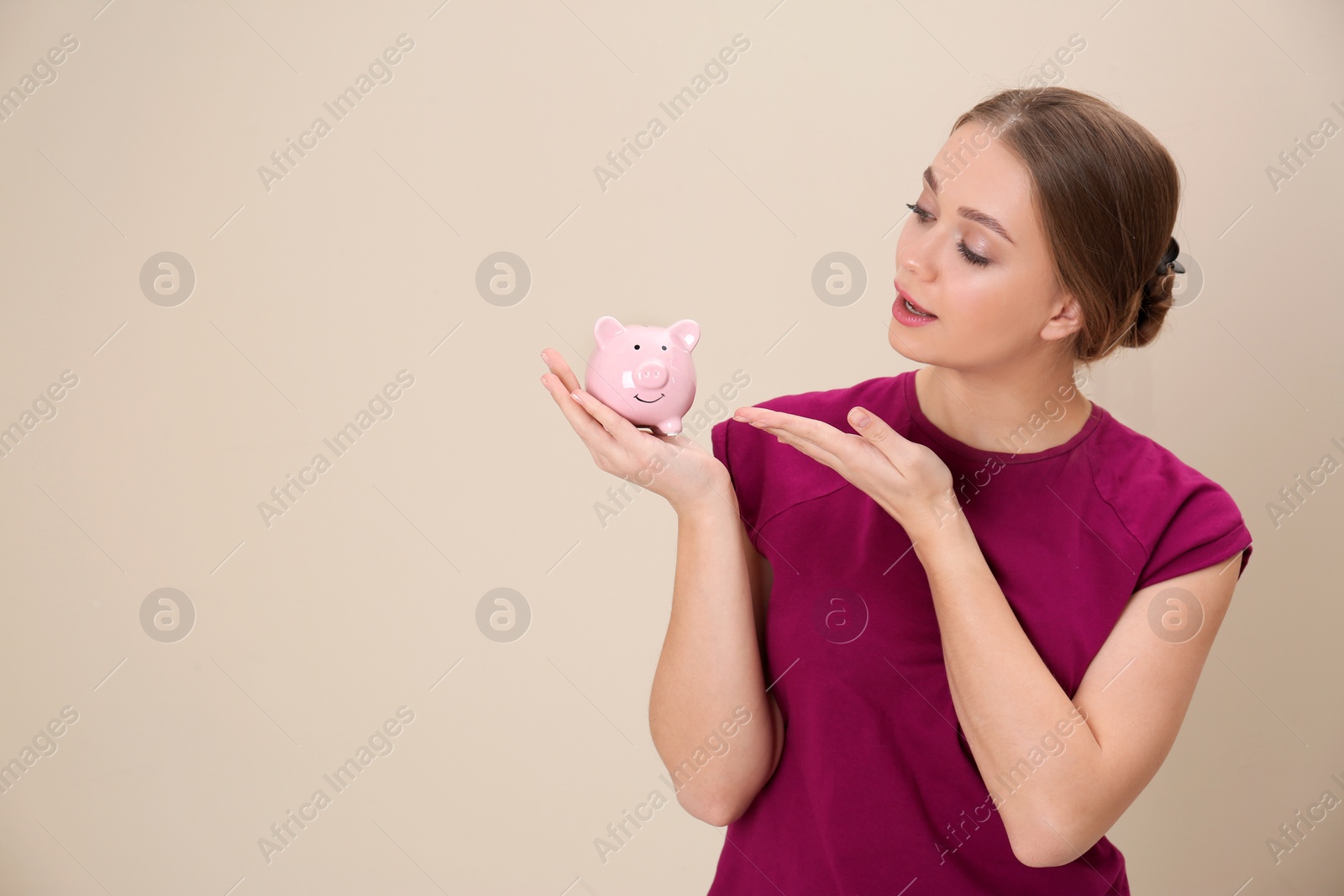 Photo of Young woman with piggy bank and space for text on color background. Money saving