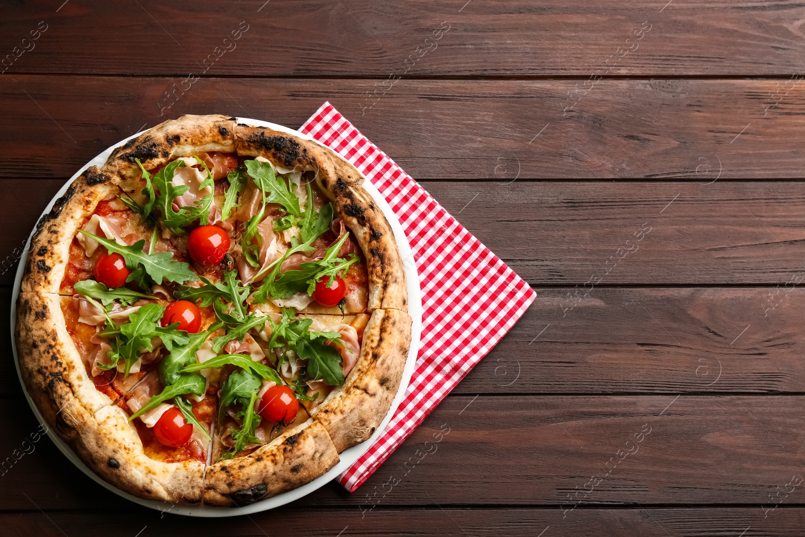 Photo of Tasty pizza with meat and arugula on wooden table, top view. Space for text