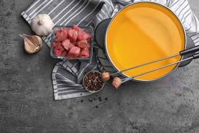 Photo of Flat lay composition with fondue pot and raw meat on grey table