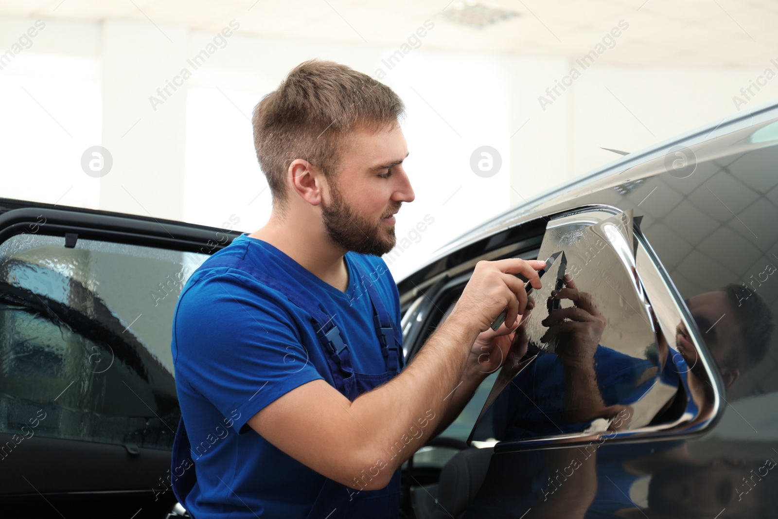 Photo of Worker tinting car window with foil in workshop