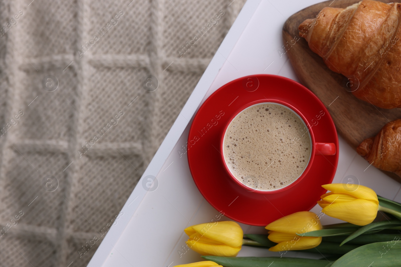 Photo of Morning coffee, croissants and flowers on knitted plaid, top view. Space for text