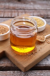 Photo of Jar with natural oil and mustard seeds on wooden table