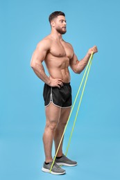 Photo of Young man exercising with elastic resistance band on light blue background