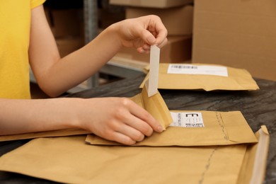 Photo of Post office worker with envelopes at counter indoors, closeup