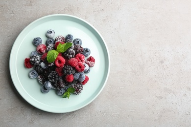 Mix of different frozen berries on grey table, top view. Space for text