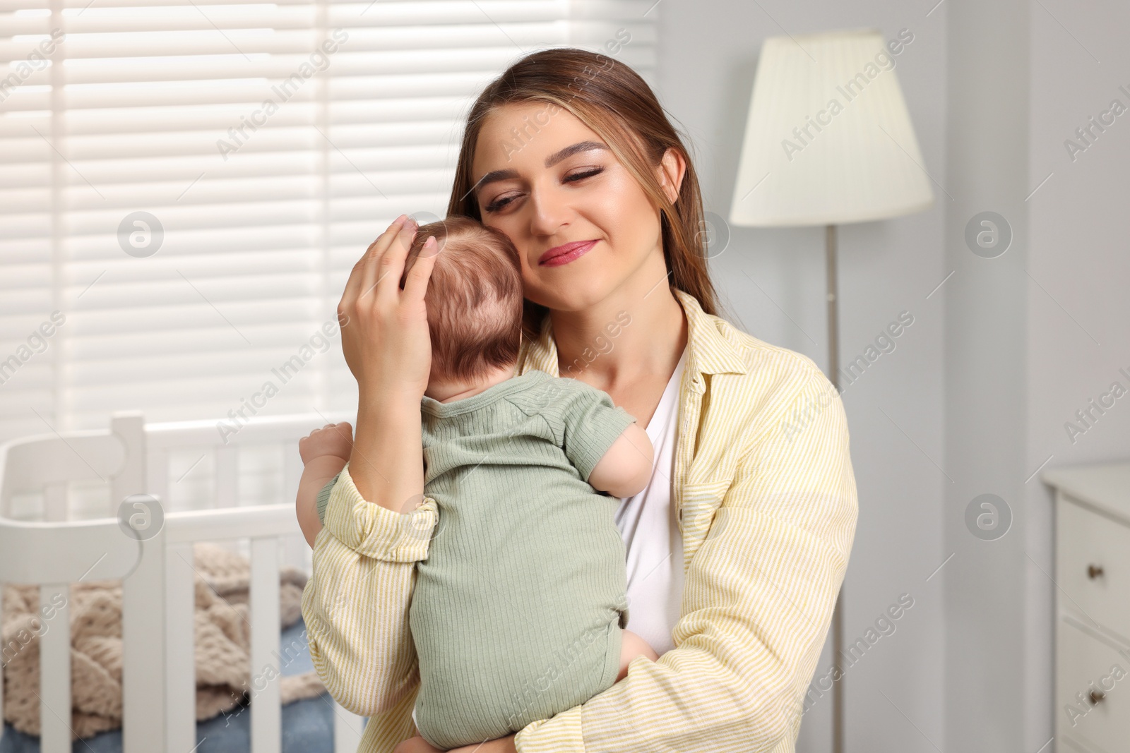 Photo of Mother holding her cute newborn baby in child's room