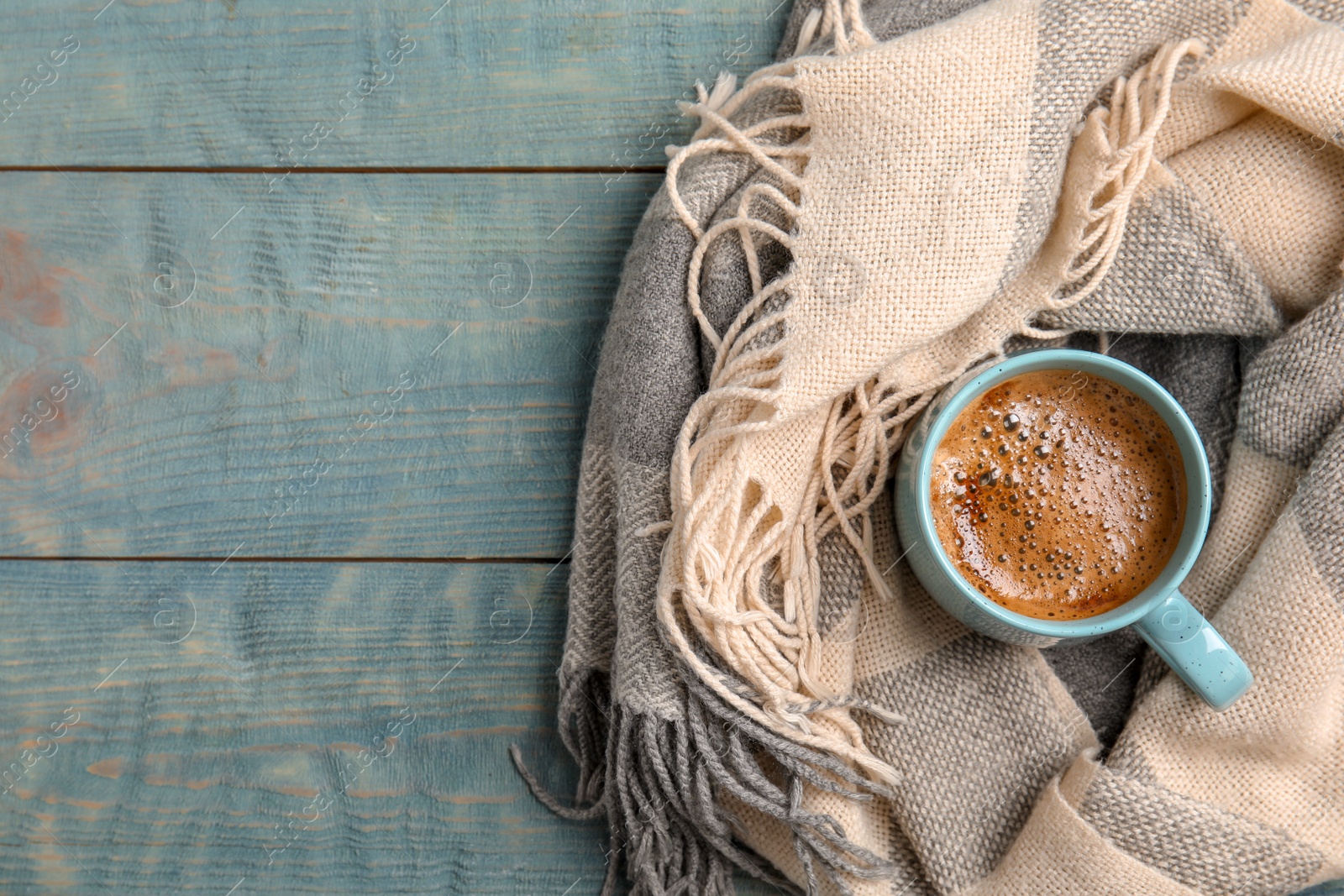 Photo of Cup of hot winter drink and warm scarf on wooden background, top view with space for text. Cozy season