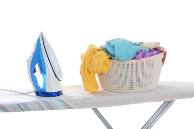 Photo of Board with modern iron and laundry basket on white background