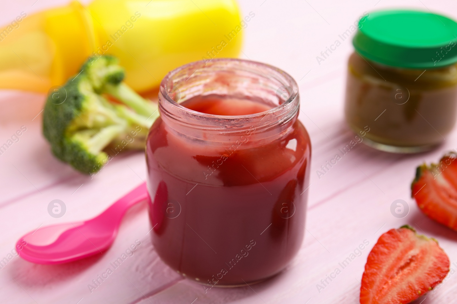 Photo of Healthy baby food and strawberry on pink wooden table