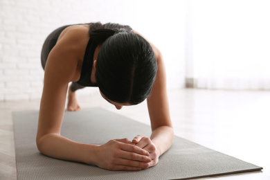Photo of Young woman practicing forearm plank asana in yoga studio. Phalankasana pose variation