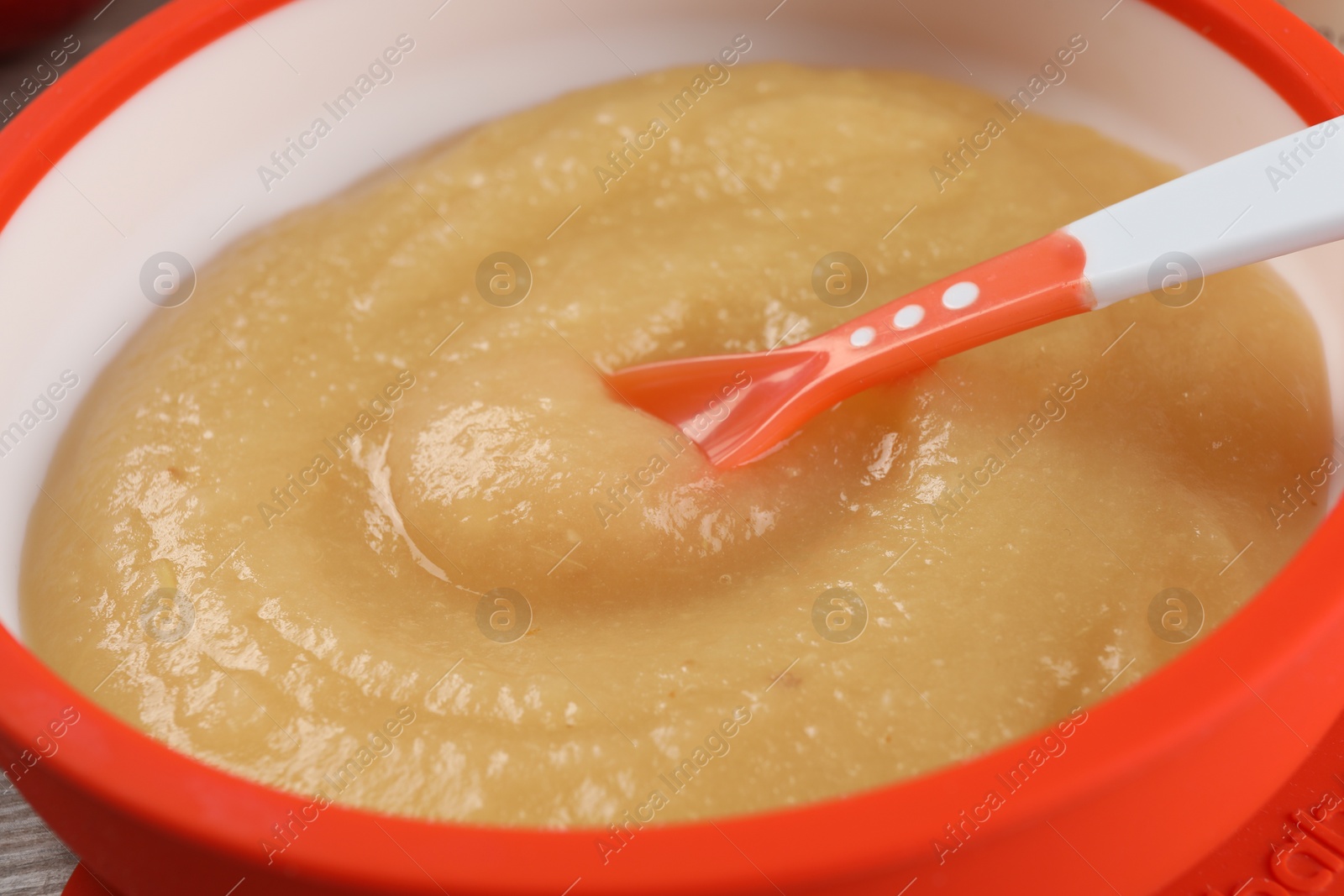 Photo of Healthy baby food. Bowl with delicious apple puree on table, closeup