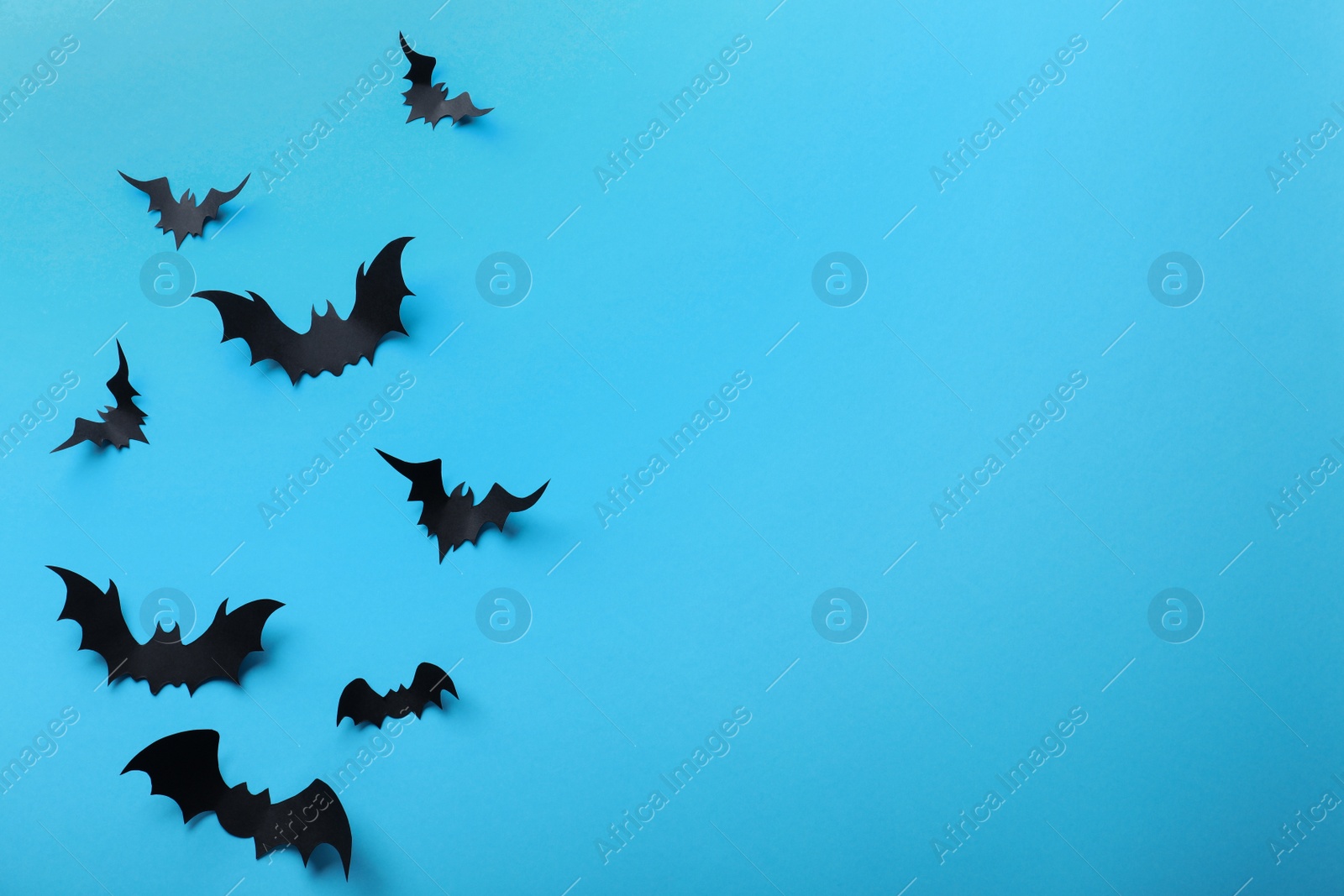 Photo of Paper bats on light blue background, flat lay with space for text. Halloween decor