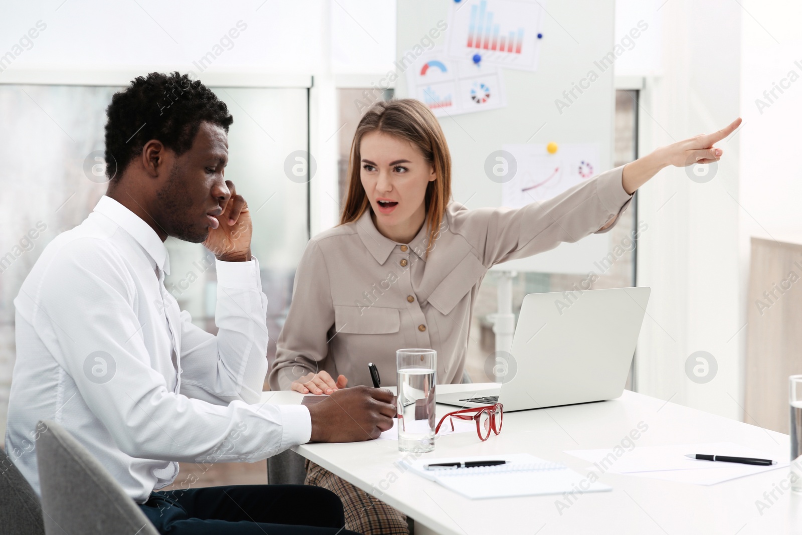 Photo of Woman screaming at African American man in office. Racism concept