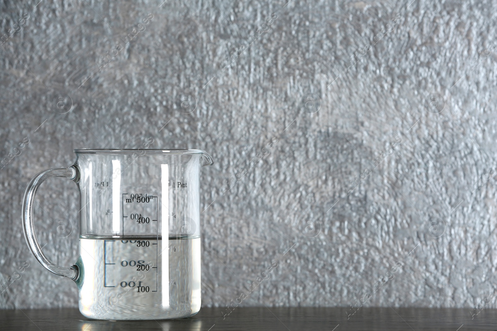 Photo of Measuring cup with vinegar on grey background. Space for text
