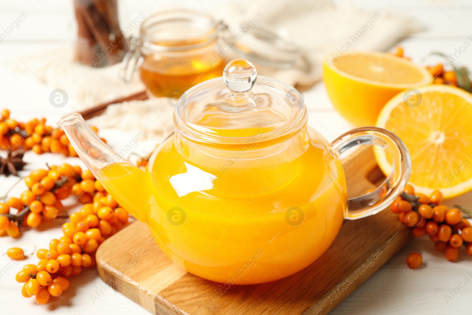 Photo of Delicious sea buckthorn tea and fresh berries on white wooden table, closeup