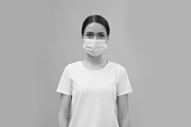 Image of Woman wearing medical face mask on light background. Black and white photography