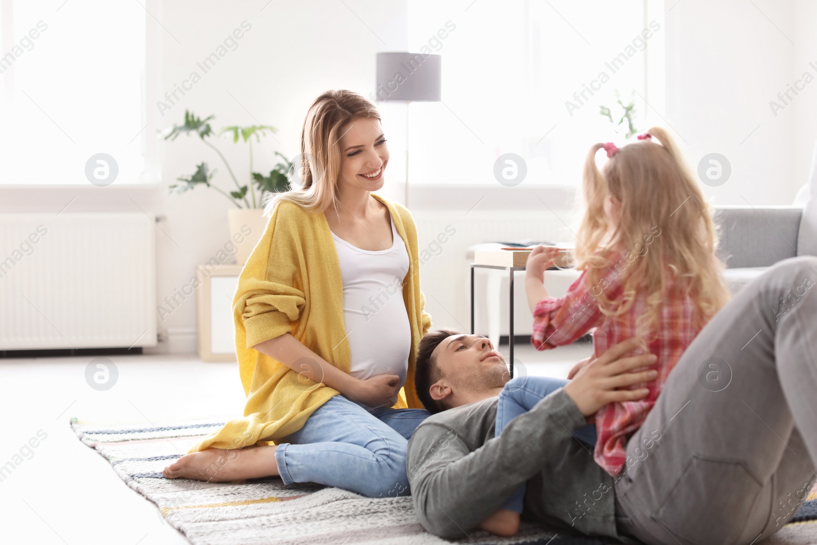 Photo of Young pregnant woman with her family at home