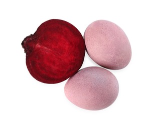 Photo of Colorful Easter eggs painted with natural dye and cut beet on white background, top view