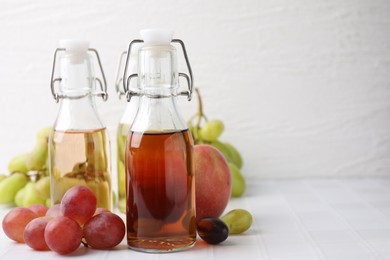 Photo of Different types of vinegar and ingredients on light tiled table, closeup. Space for text