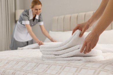 Chambermaid putting fresh towels on bed in hotel, closeup