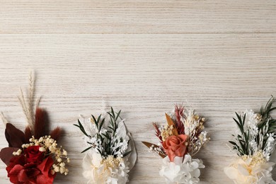 Photo of Stylish boutonnieres on white wooden table, flat lay. Space for text