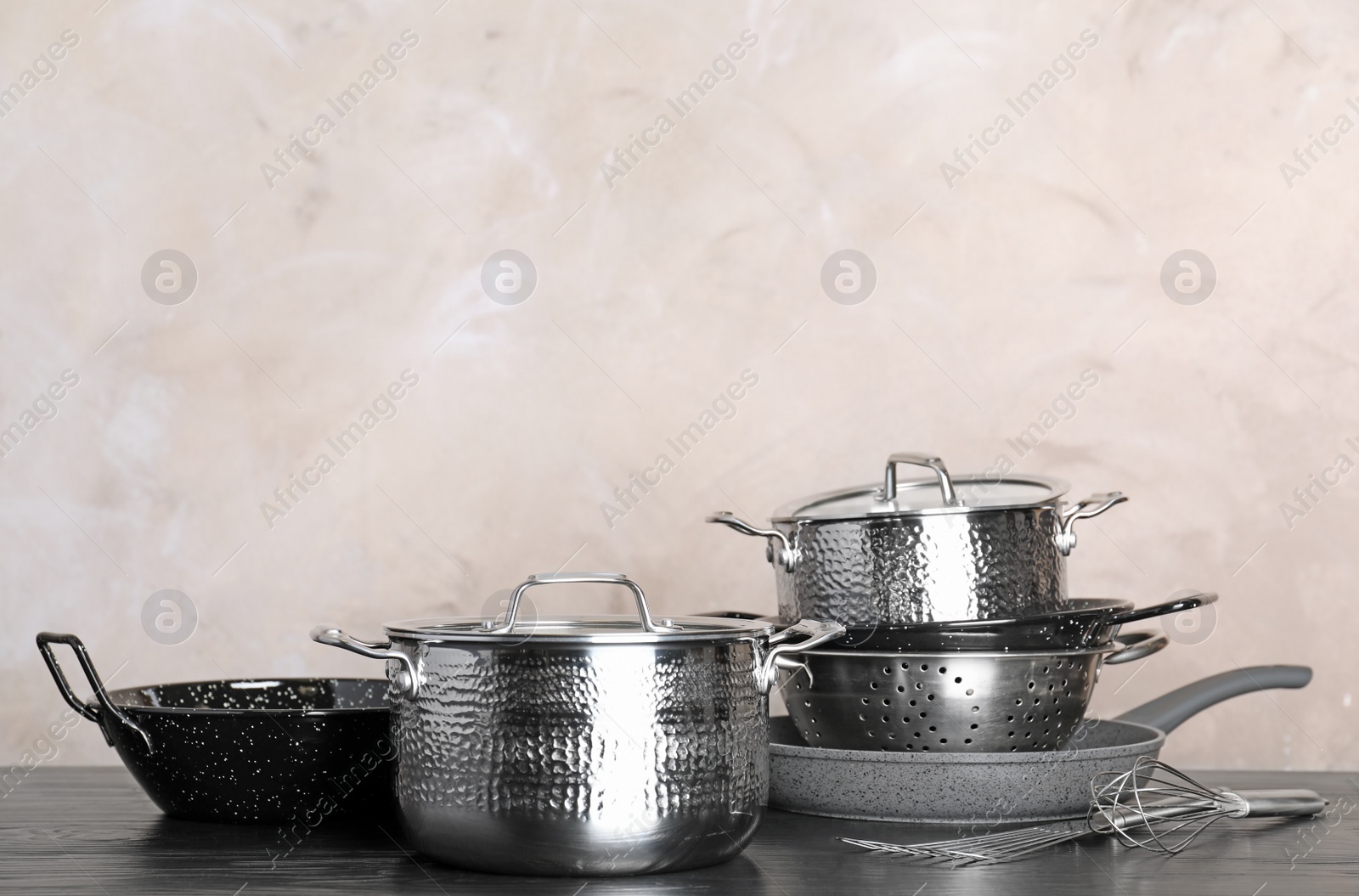 Photo of Set of clean cookware and utensils on table against color background, space for text