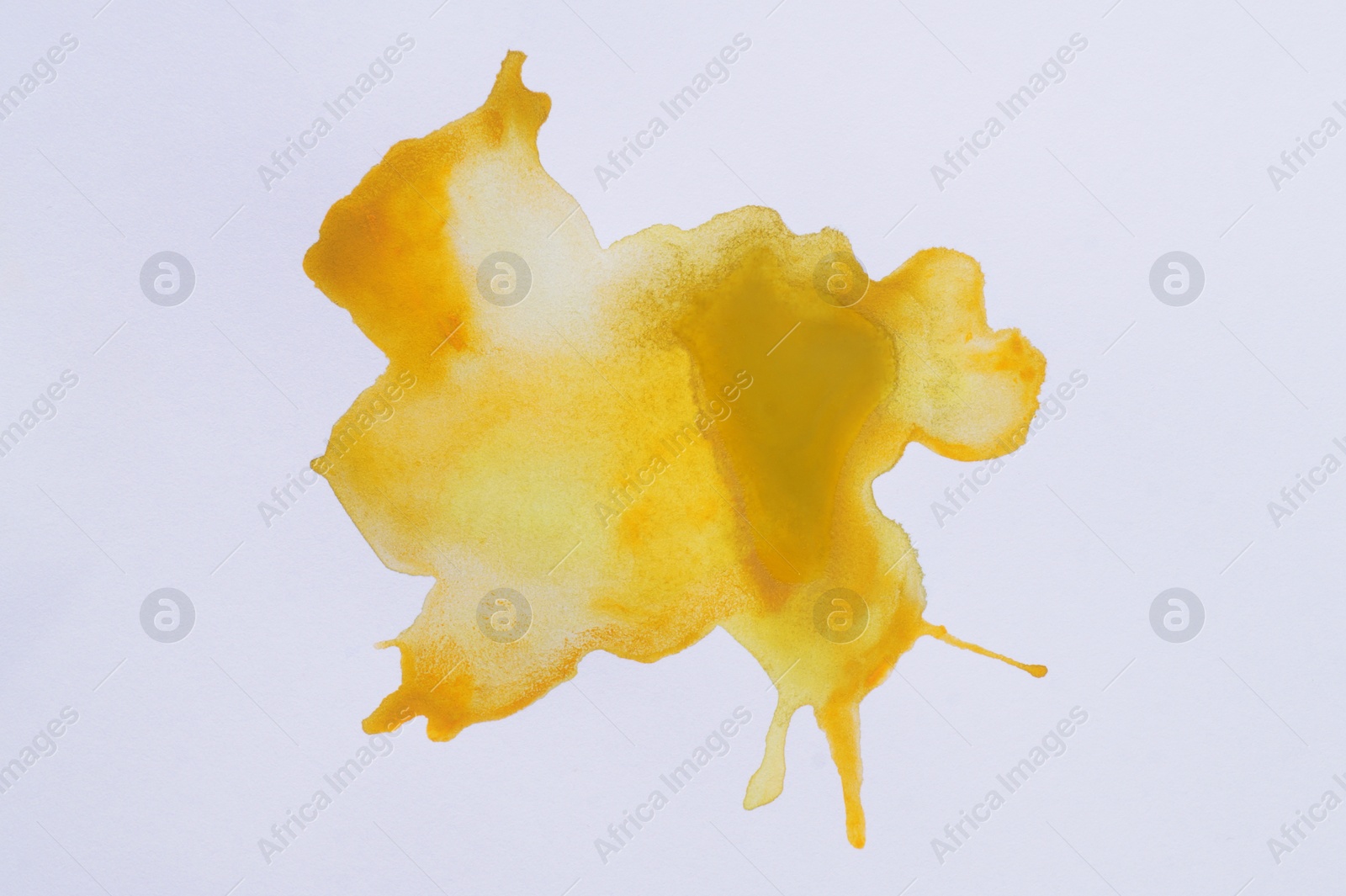 Photo of Blot of yellow watercolor paint on white paper, top view