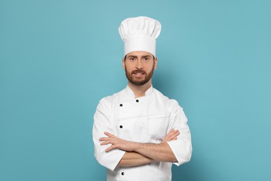 Photo of Smiling mature chef on light blue background, space for text