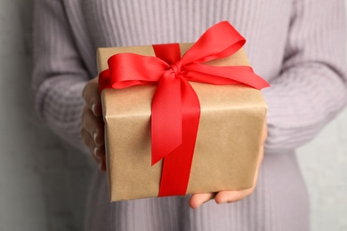 Photo of Young woman holding Christmas gift, closeup view