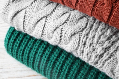 Photo of Stack of soft knitted sweaters on table, closeup