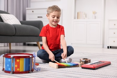 Photo of Little boy playing toy xylophone at home