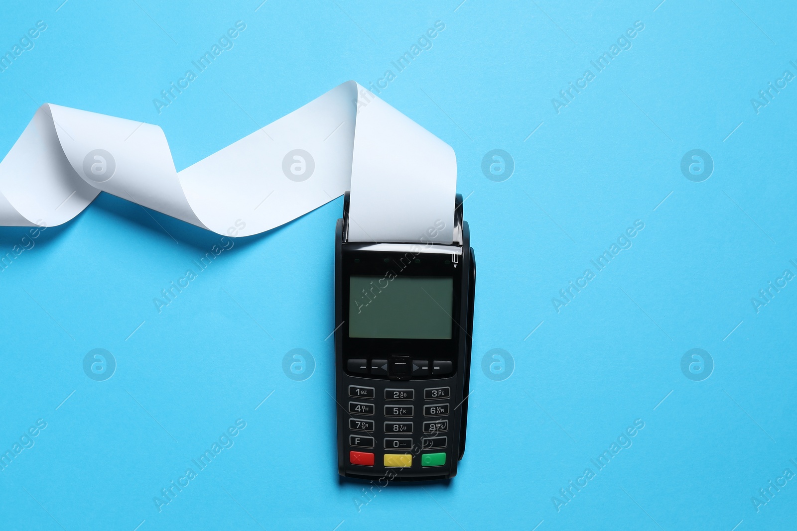 Photo of Payment terminal with thermal paper for receipt on light blue background, top view