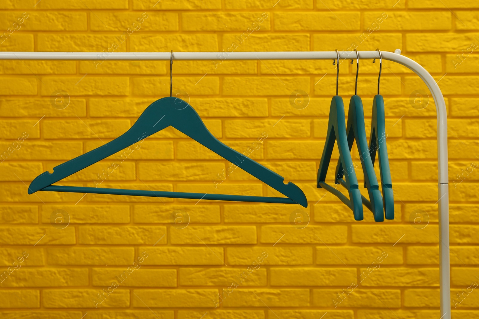 Photo of Wardrobe rack with many hangers near yellow brick wall