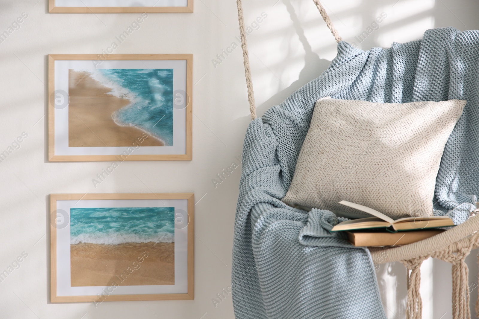 Photo of Different pictures on wall and hanging chair in room. Artworks in interior design